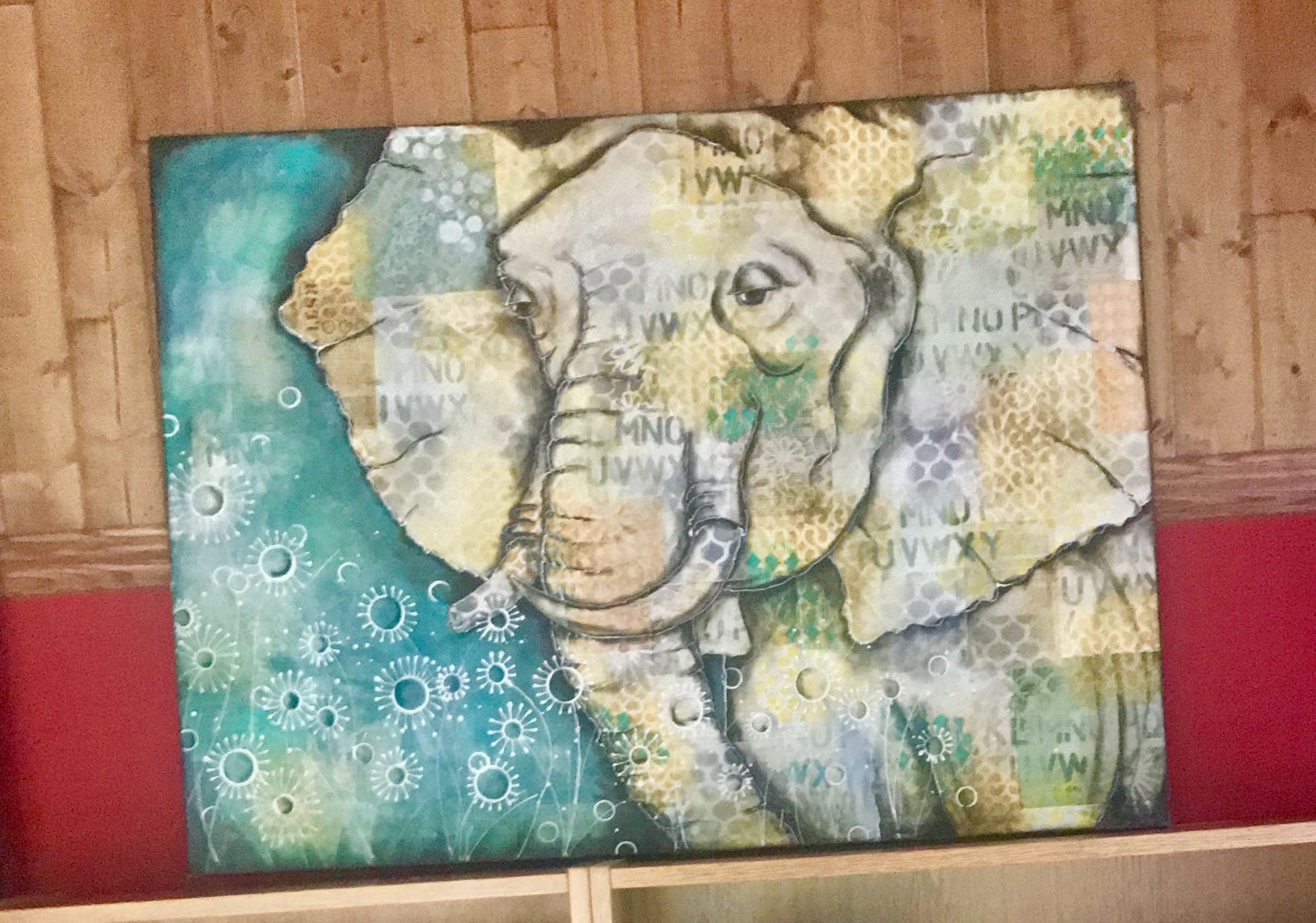 A mixed media canvas of an elephant sitting on a shelf in an office