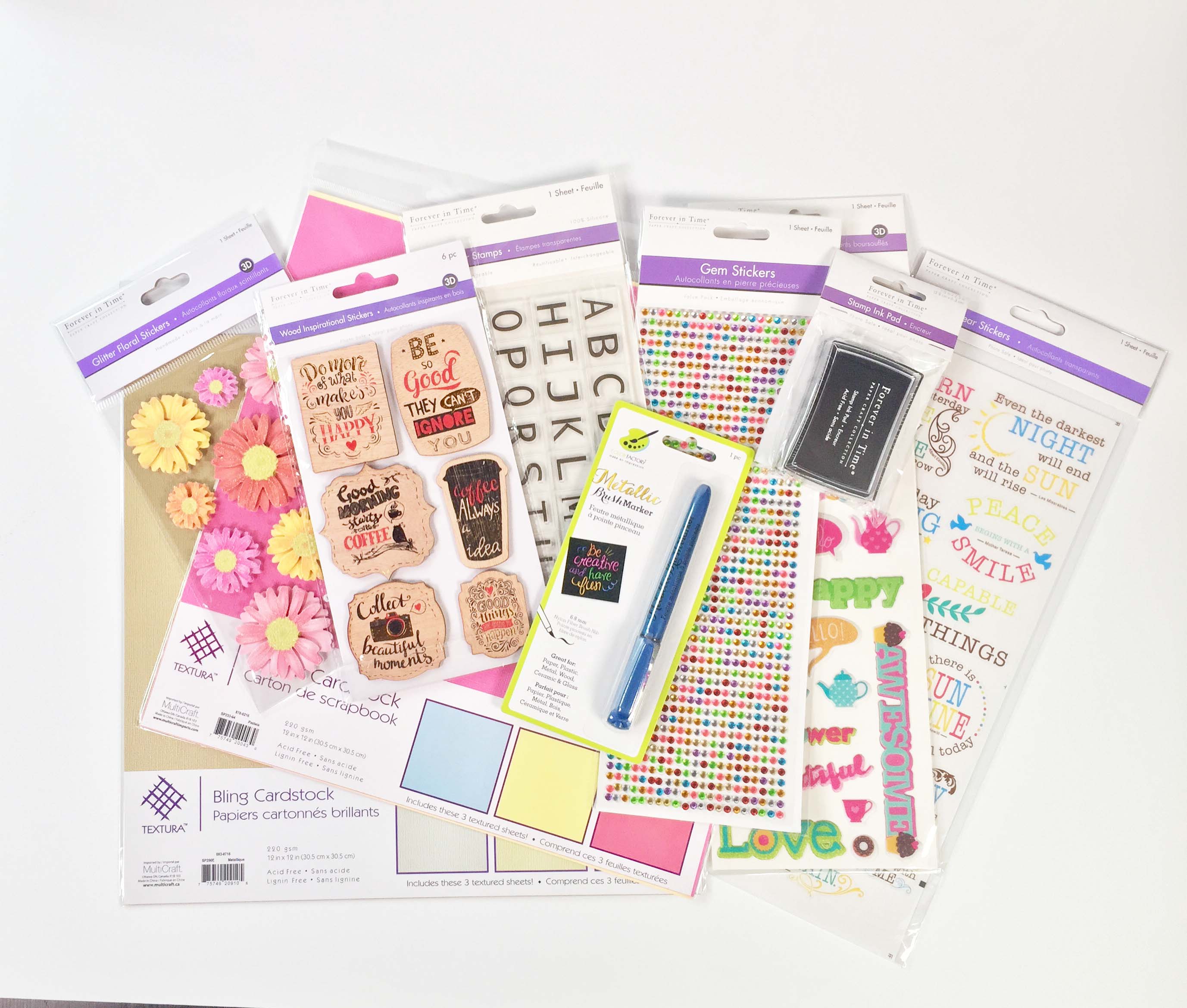 A collection of paper crafting products from MultiCraft Forever in Time including stickers, patterned paper, cardstock, ink, pens, alphabet stamps and flower die cut stickers.