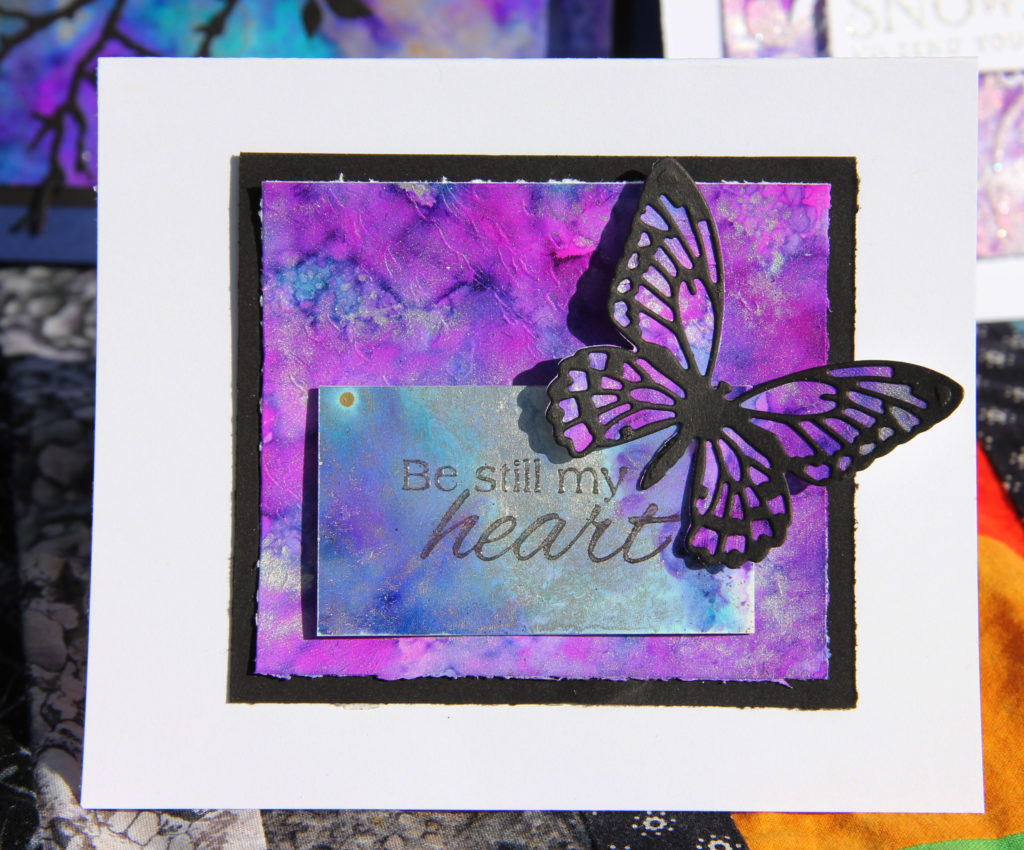 Butterfly scrapbook card in bright purples and blues featuring Ranger Tim Holtz Alcohol Ink Yupo paper and alcohol inks. Card designed by Jayme Loge
